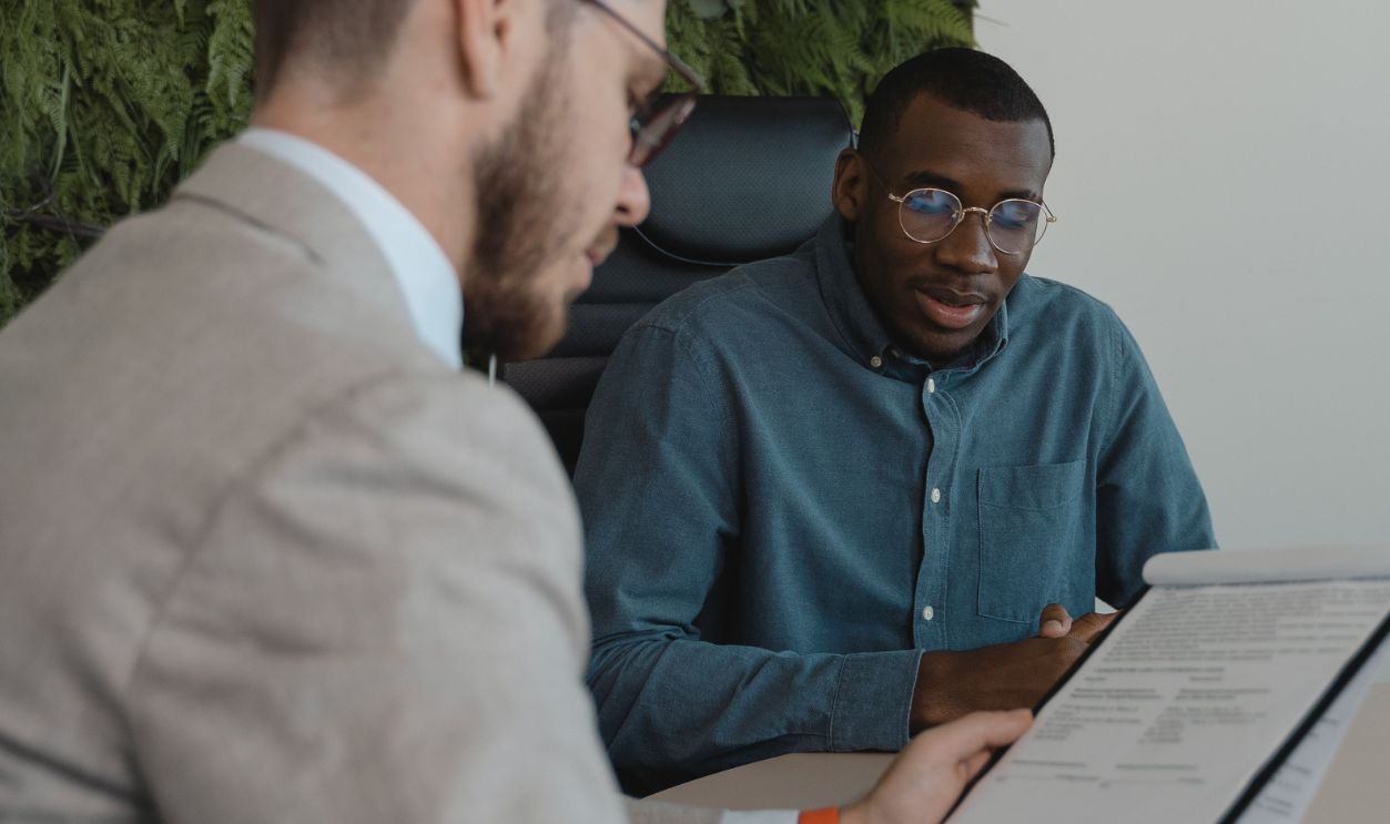 Two men in a modern office setting discussing a document during a business meeting