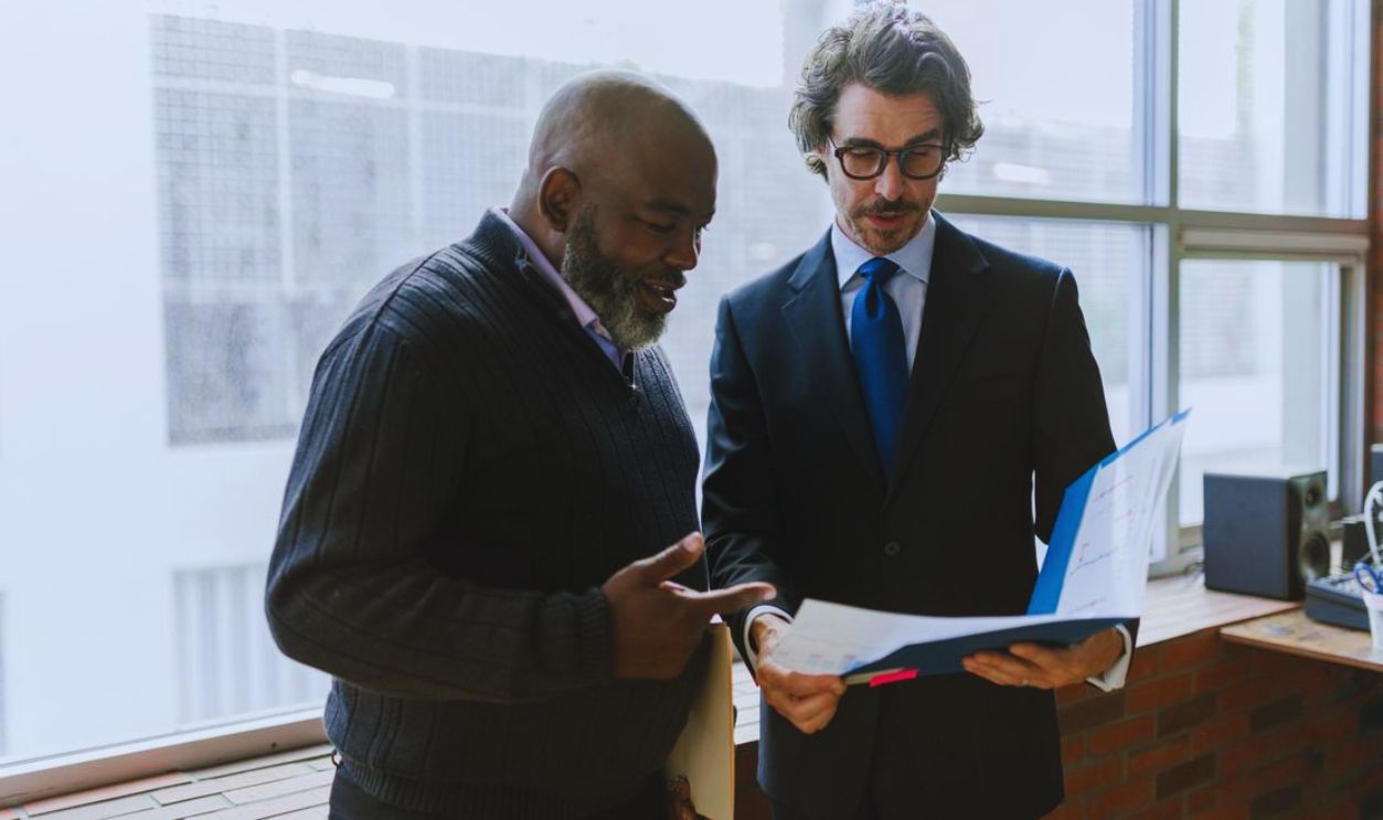 Two businessmen discussing and reviewing documents in a modern office setting