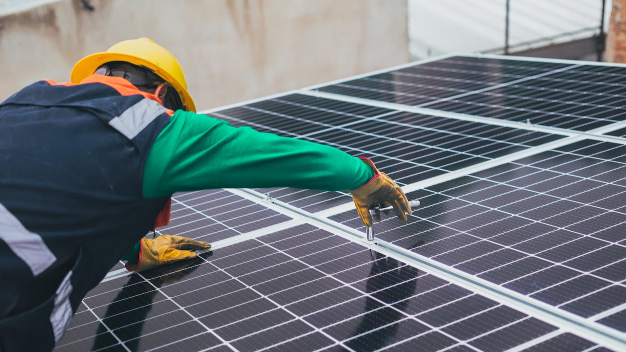 Technician installing solar panels on a rooftop for sustainable energy solutions.
