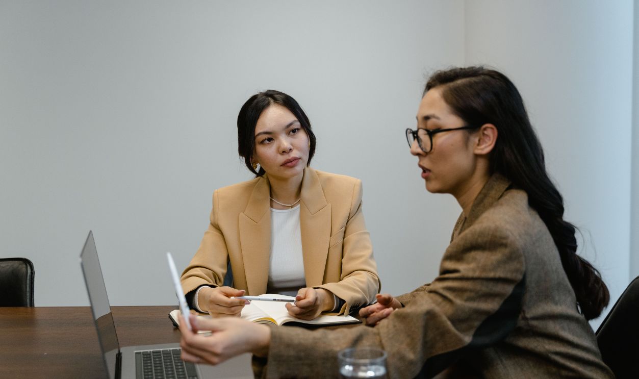 Two Asian businesswomen in a professional meeting discussing work