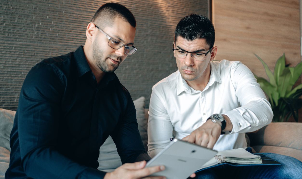 Two men collaborating on a digital tablet indoors