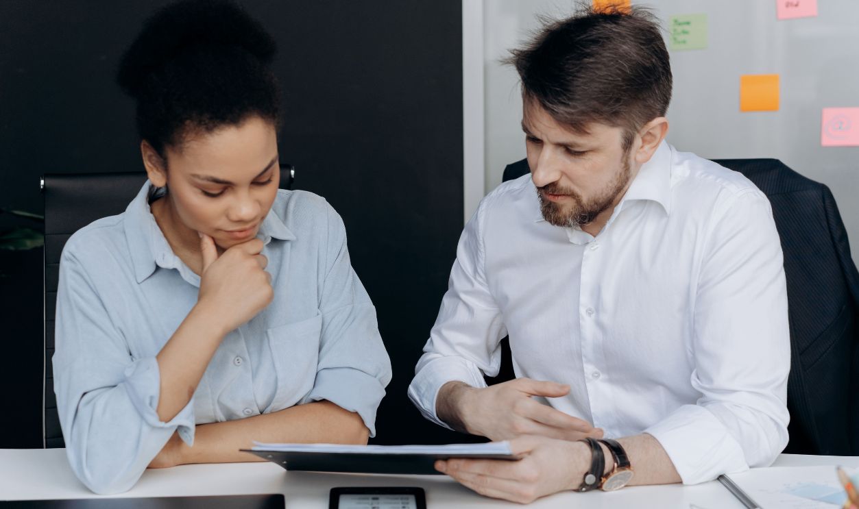 Two colleagues discussing project details in a modern office