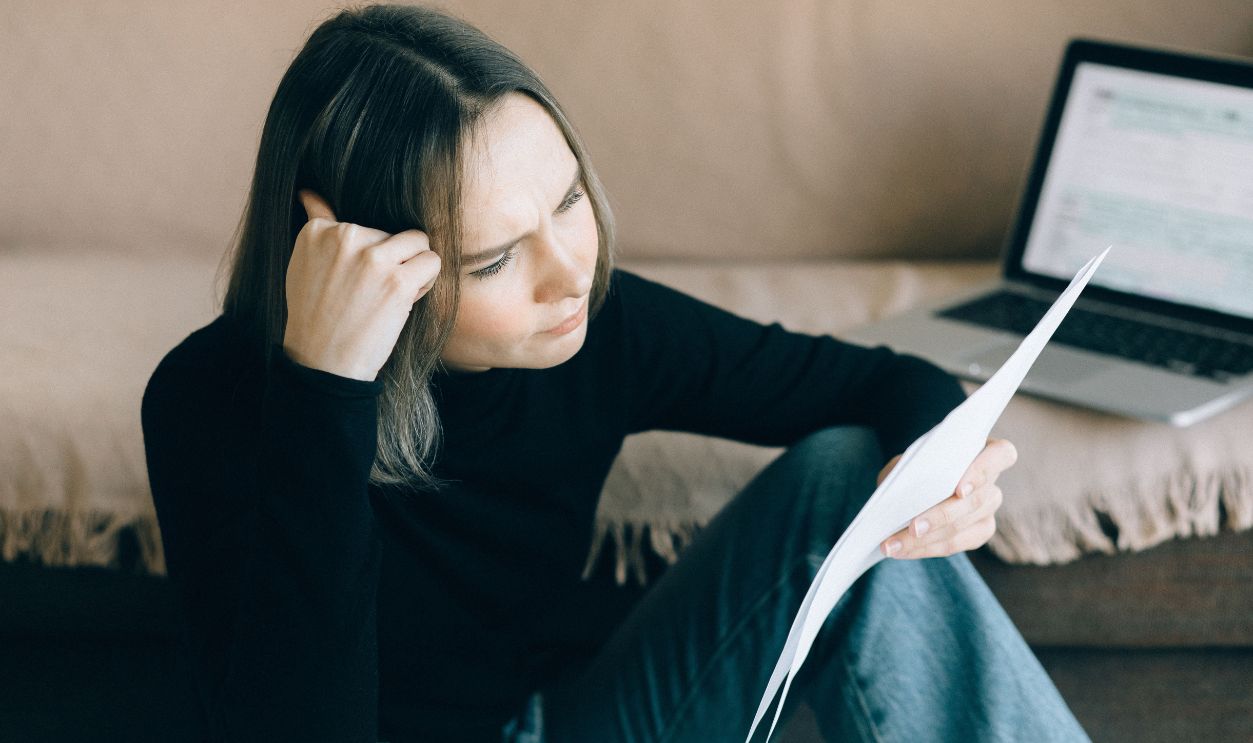 Focused woman analyzing document with a laptop open