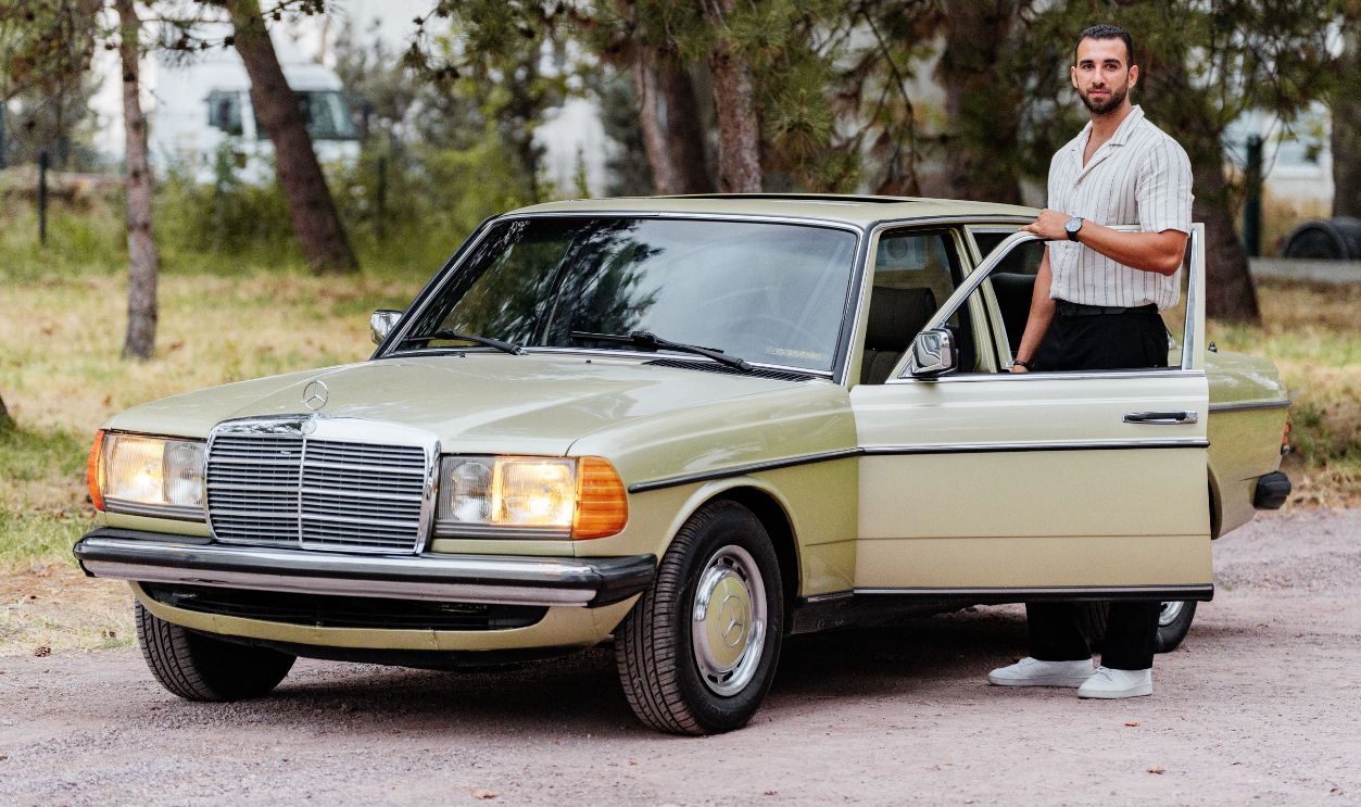A classic vintage car with its driver standing beside it 