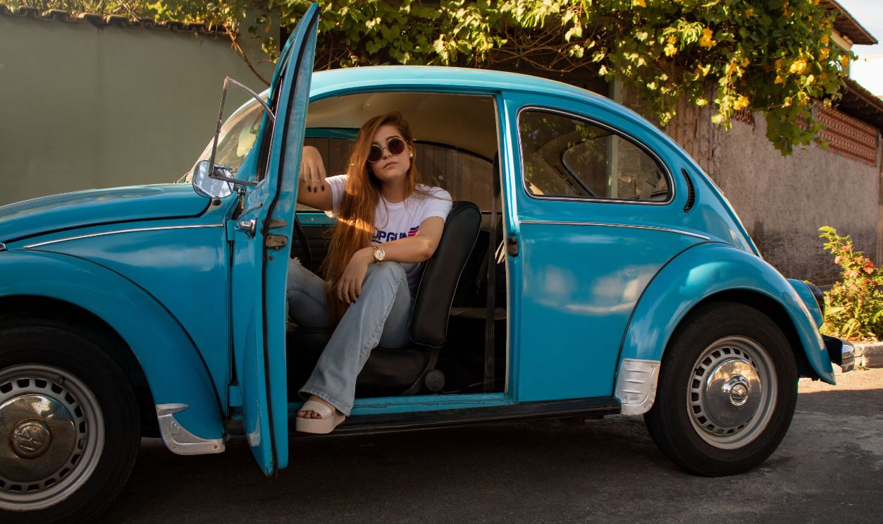 A stylish woman posing in a classic blue Volkswagen Beetle 