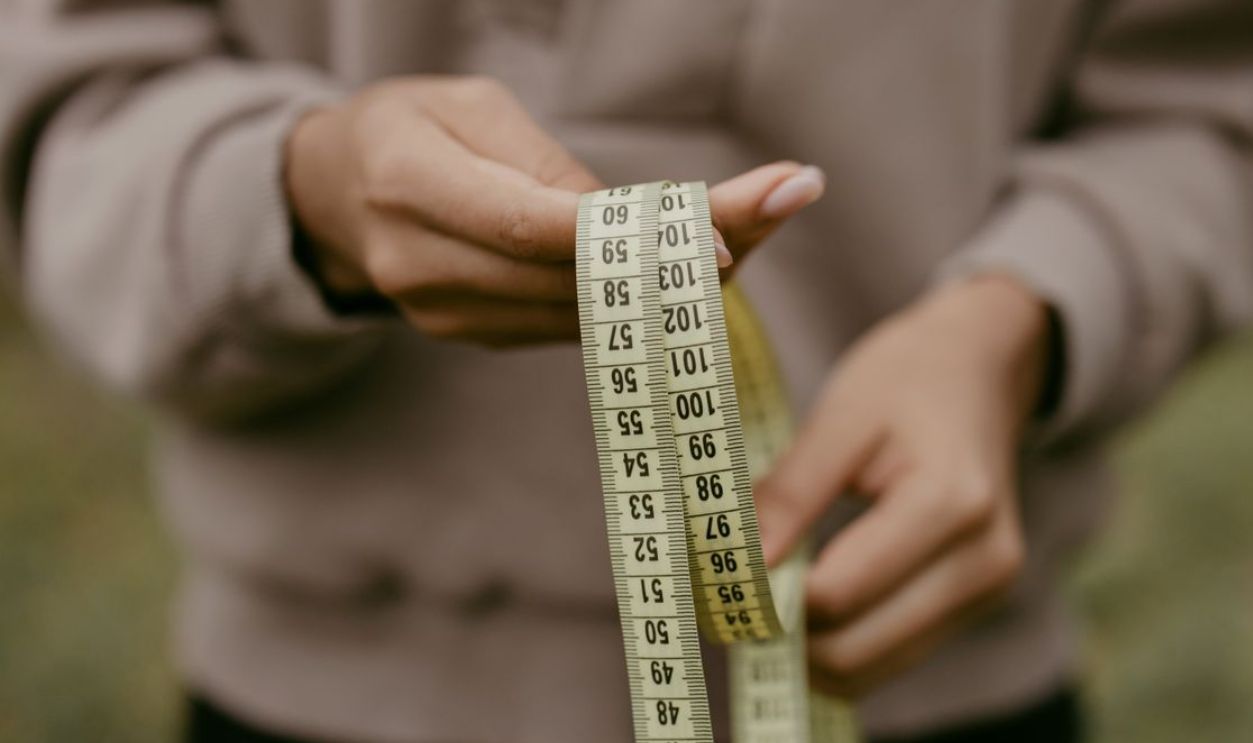 Hands holding a yellow tape measure, perfect for concepts like construction or sewing