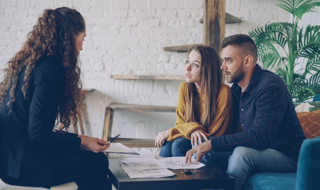 Young couple consulting with a business advisor in a modern office setting.