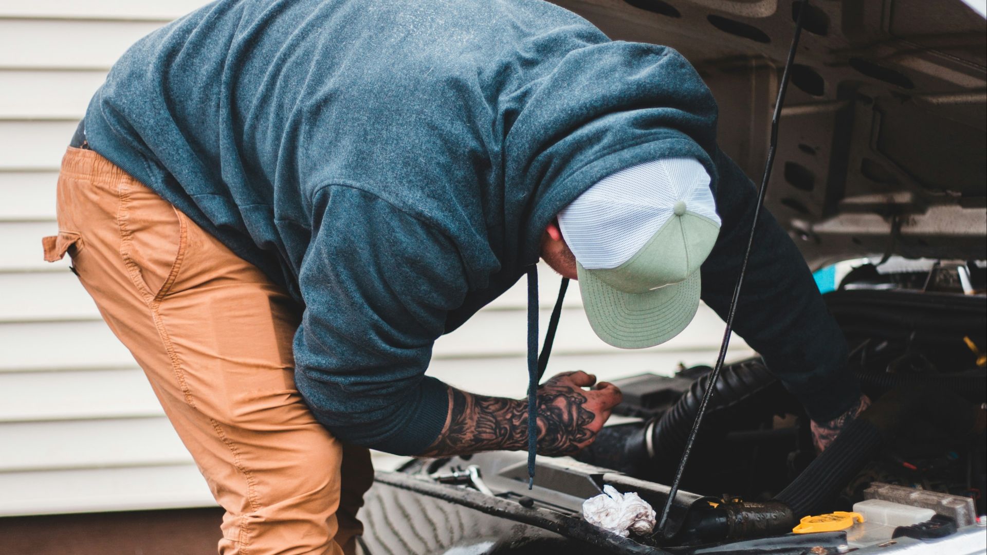 man in blue long sleeve shirt and brown pants standing beside black car
