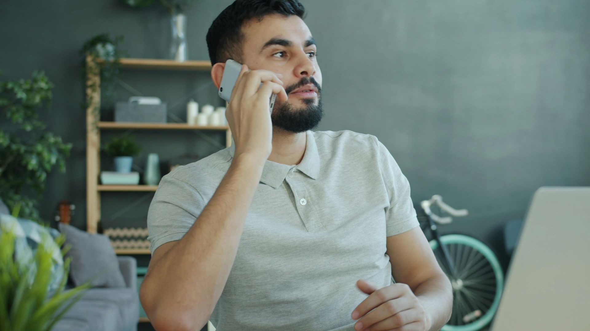 Man talking on phone at desk with laptop.