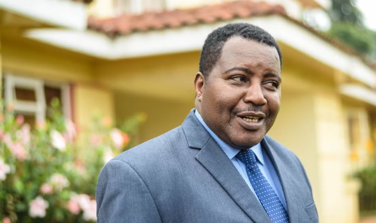 Confident African American man in a suit smiling outside a building with plants