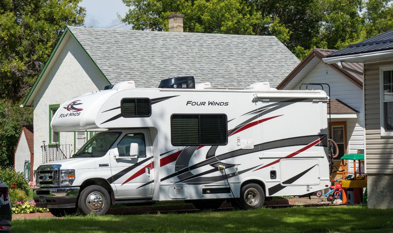 Brooks, Alberta - July 20, 2025: A self-driving RV parked in front of a small wooden house with a tiled roof