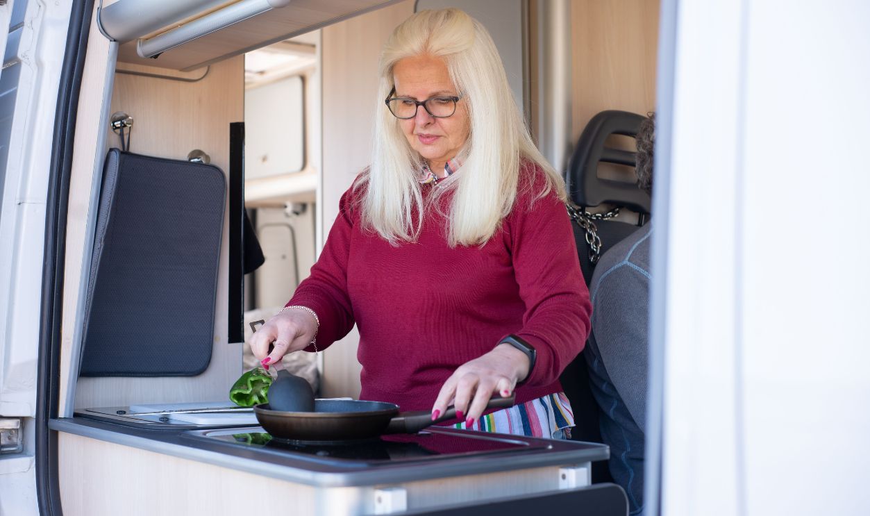 Senior woman preparing a meal in a motorhome kitchen, embracing travel and lifestyle freedom