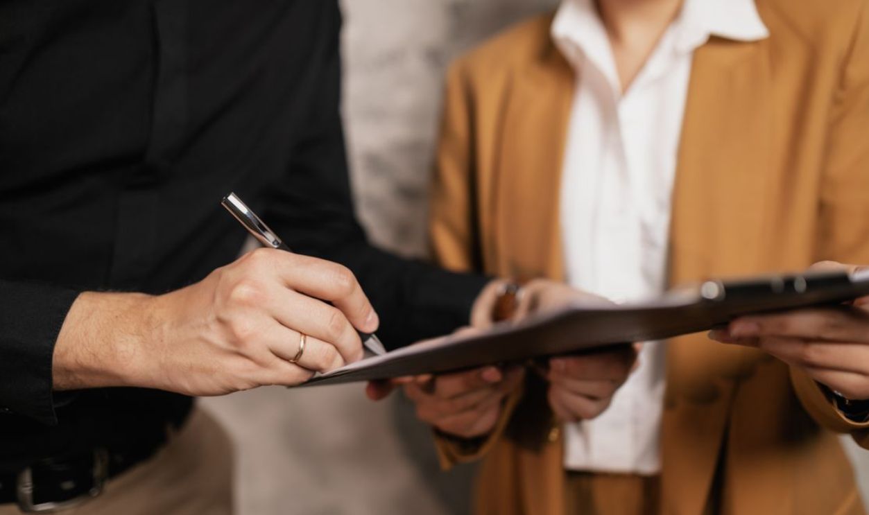 Close-up of two professionals signing a document indoors, focus on hands and pen