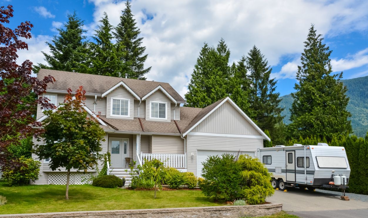 Big residential house with RV trailer parked on driveway. Family house on country side in British Columbia, Canada