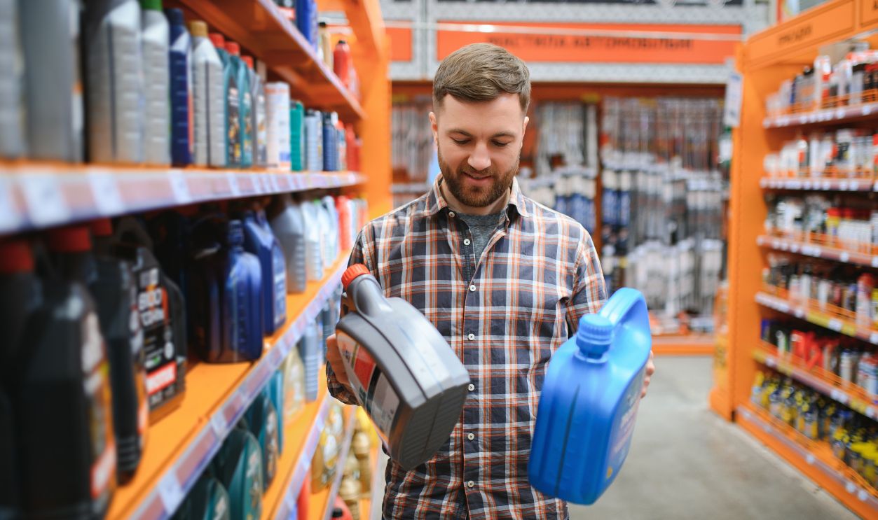 seller man with canister of motor oil in auto store.