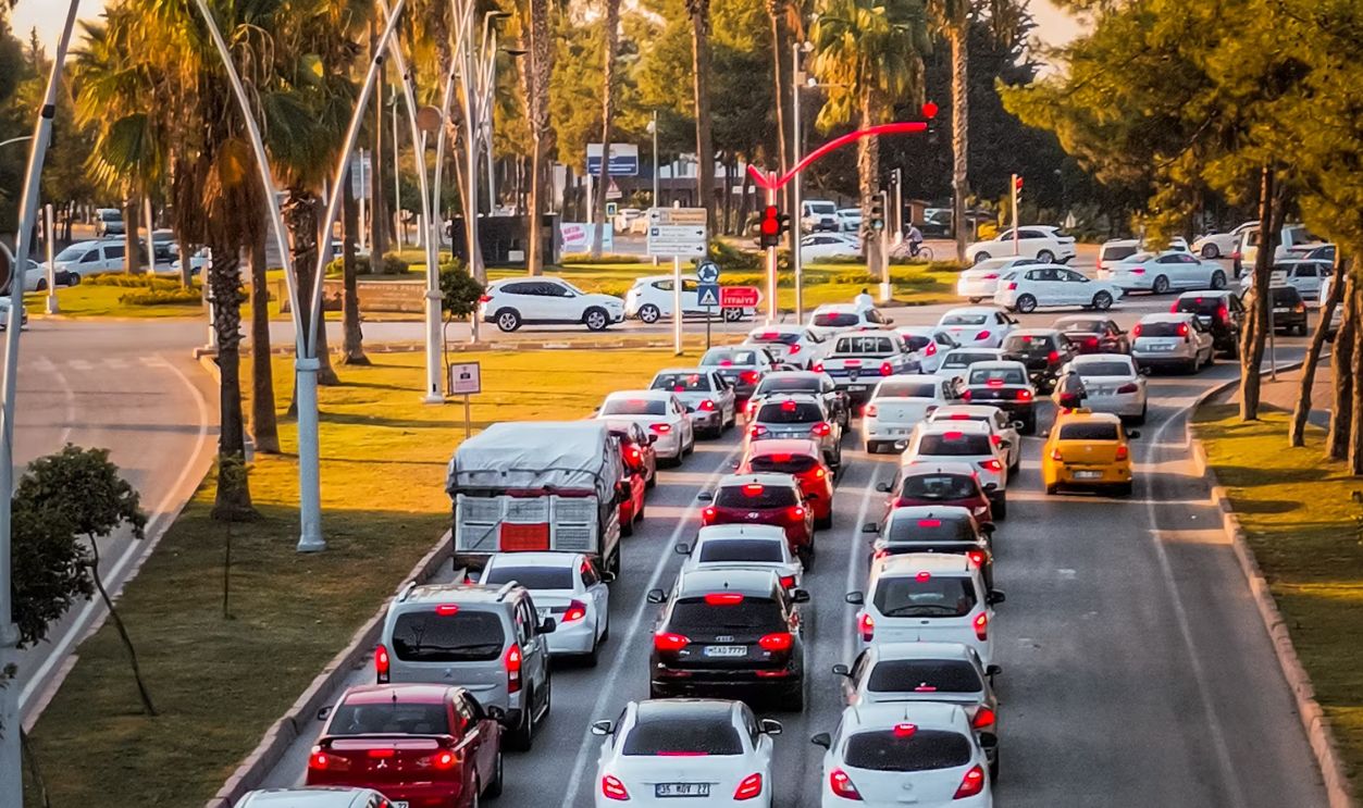 Aerial view of cars stuck in urban traffic during daylight, surrounded by palm trees