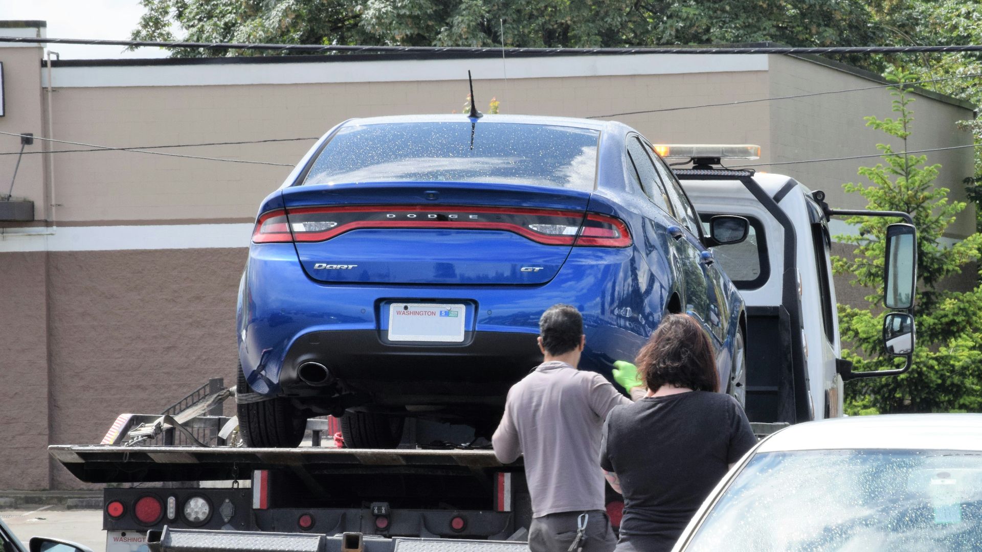 a blue car being loaded onto a flatbed truck