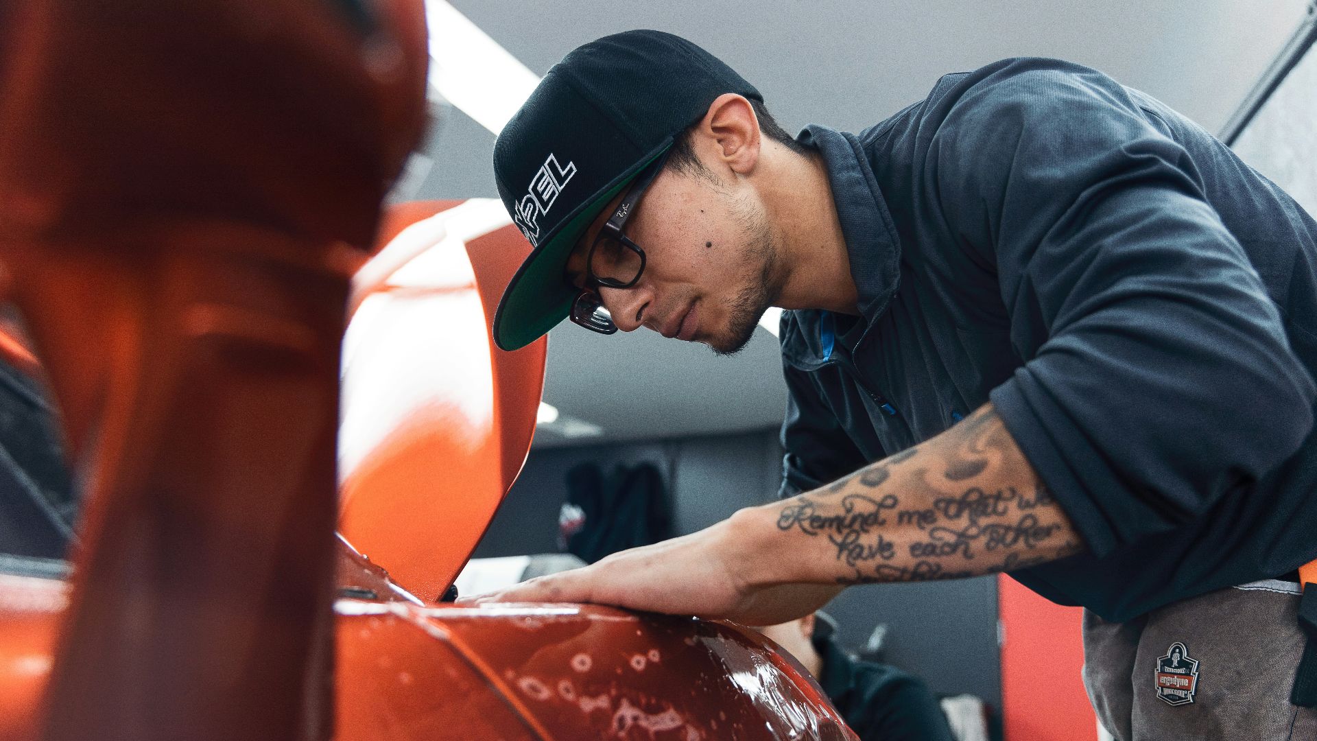 a man in a black shirt and hat waxing a car