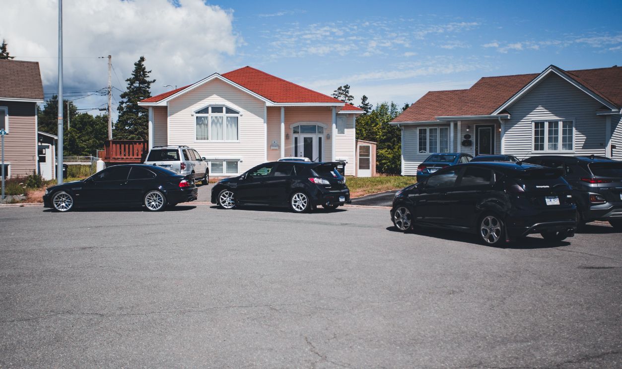 A quiet suburban street with parked cars in front of modern houses 