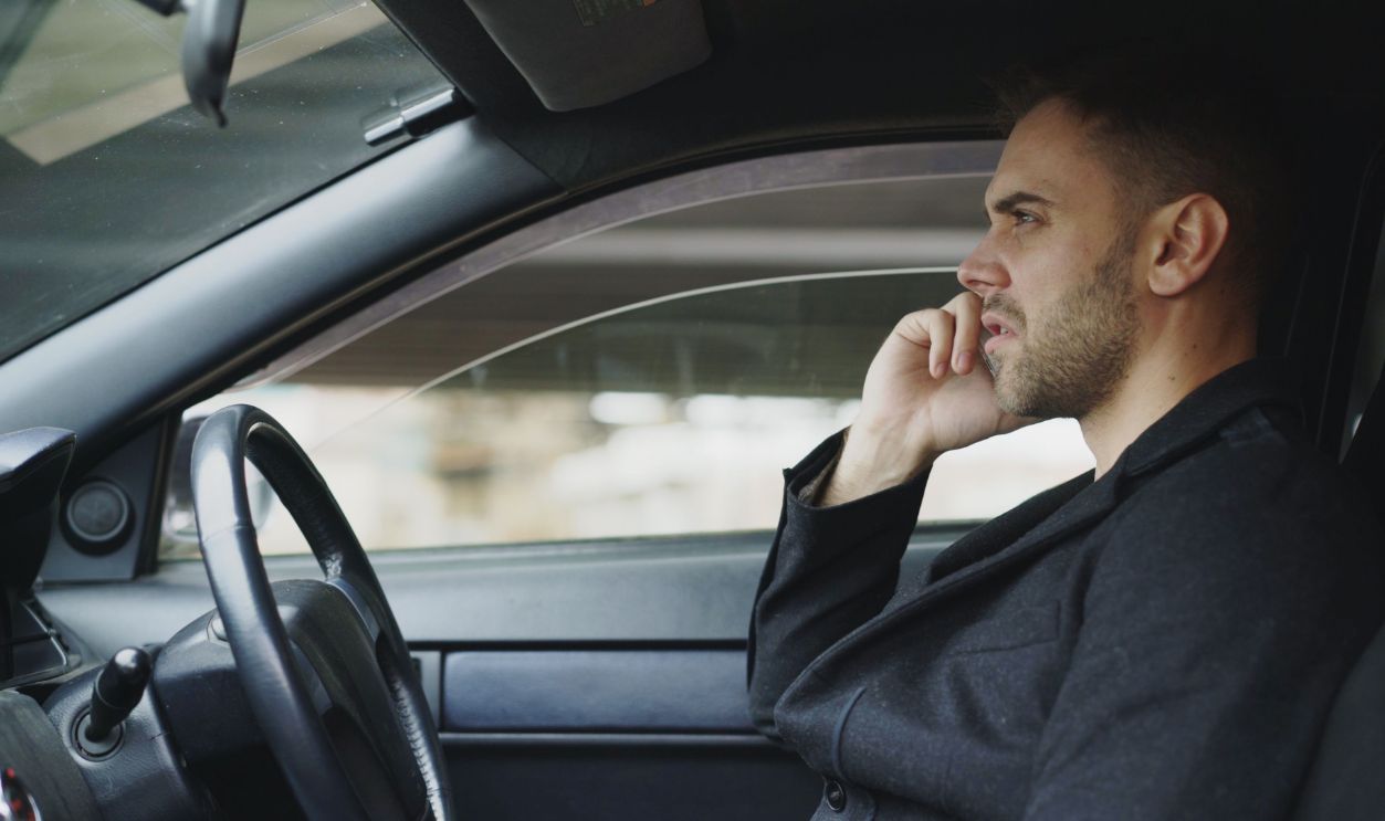 Focused man talking on smartphone in a car during the day