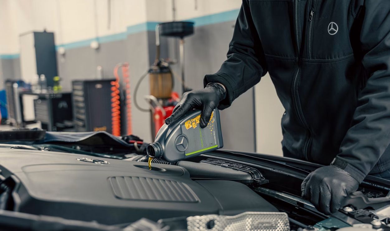 Mechanic pouring oil into car engine