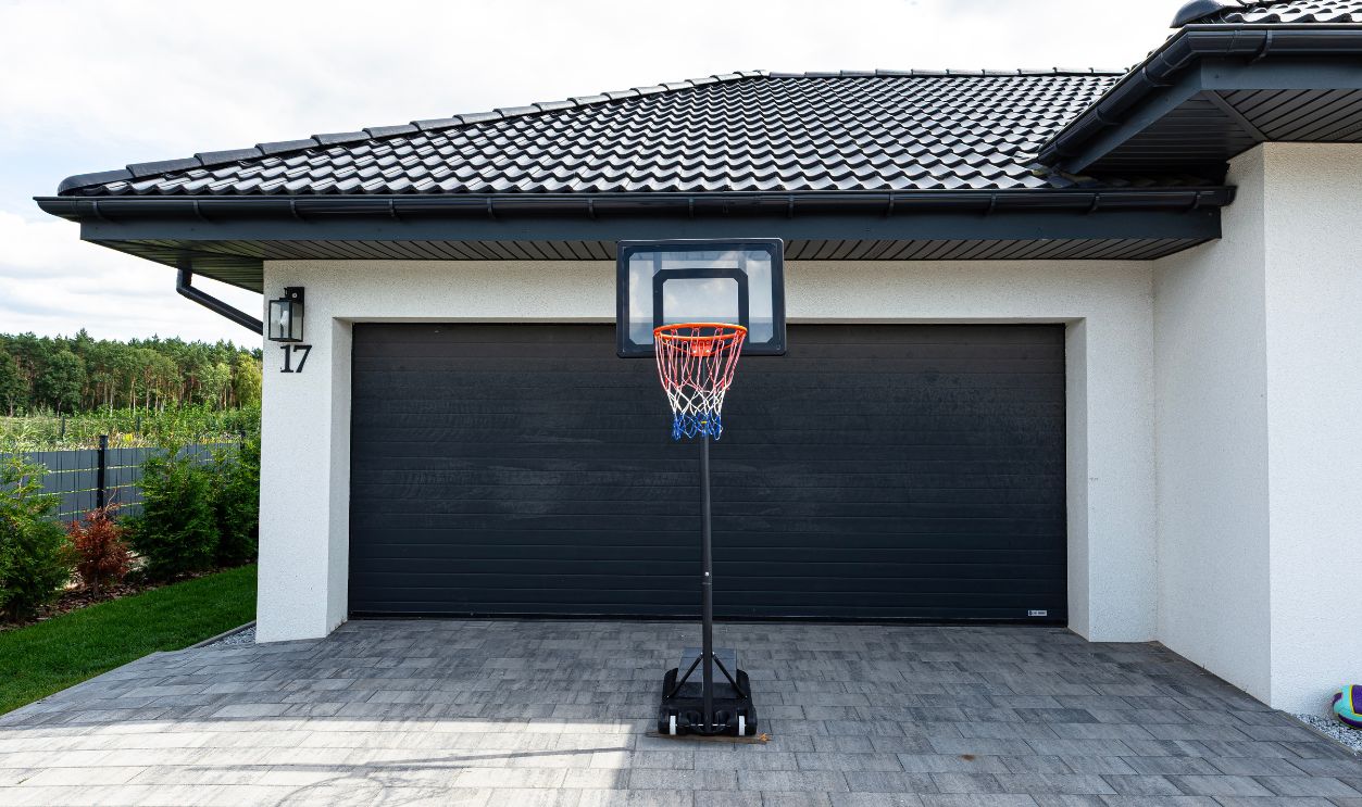 Portable basketball hoop set up on a paved driveway in front of a garage door