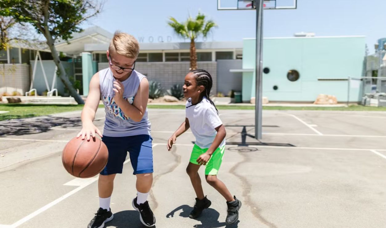 Two kids enjoying a game of basketball outdoors, showcasing fun and friendship.