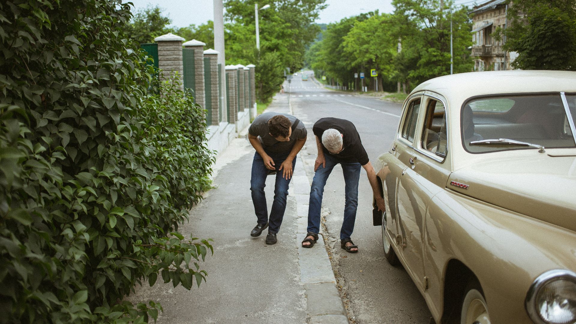 men looking on car tire
