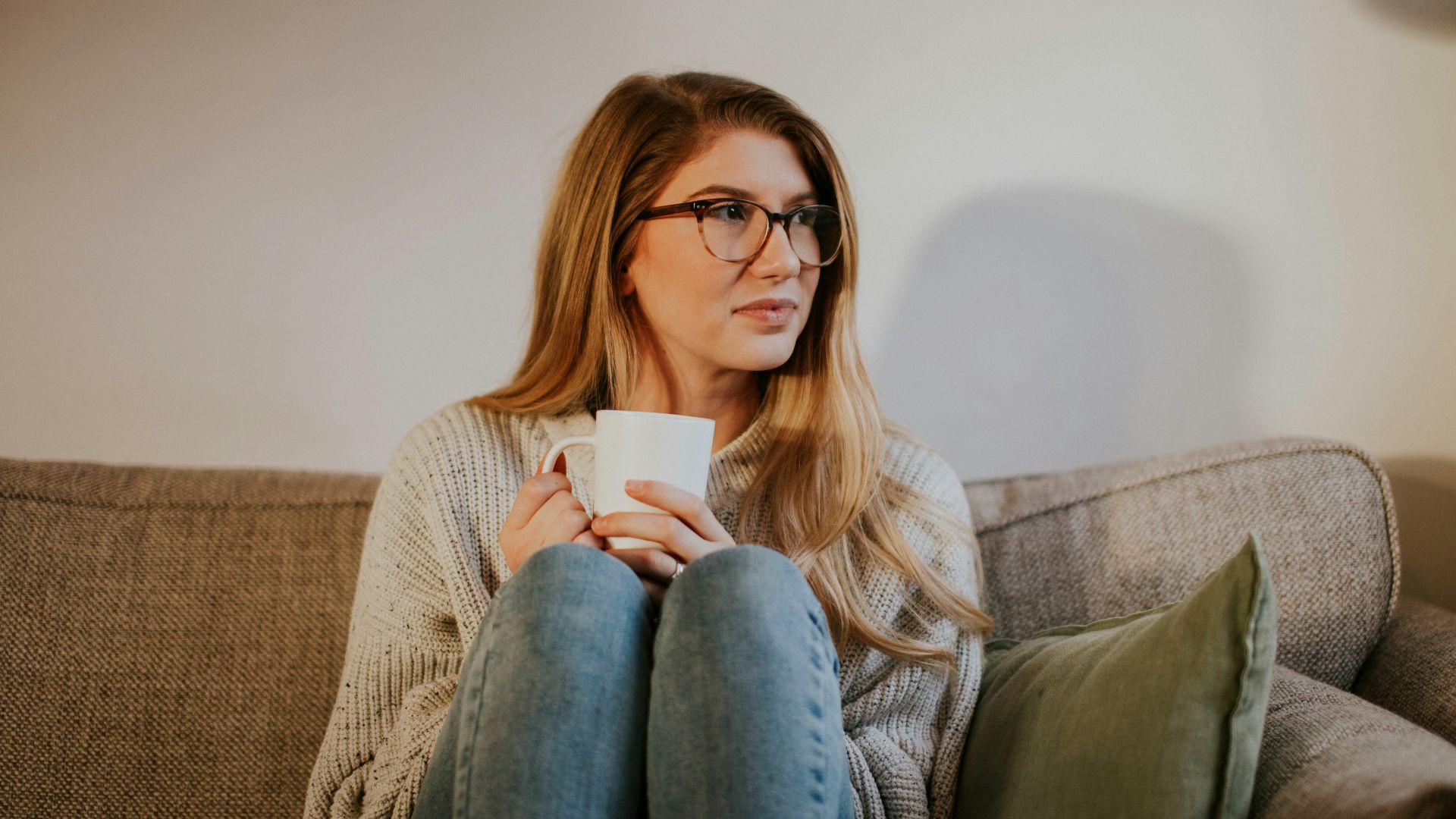 woman in blue denim jeans sitting on gray sofa