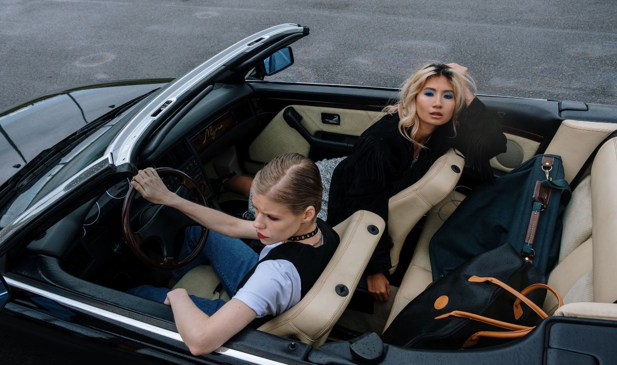 Two stylish women driving in a sleek black convertible, embracing adventure 