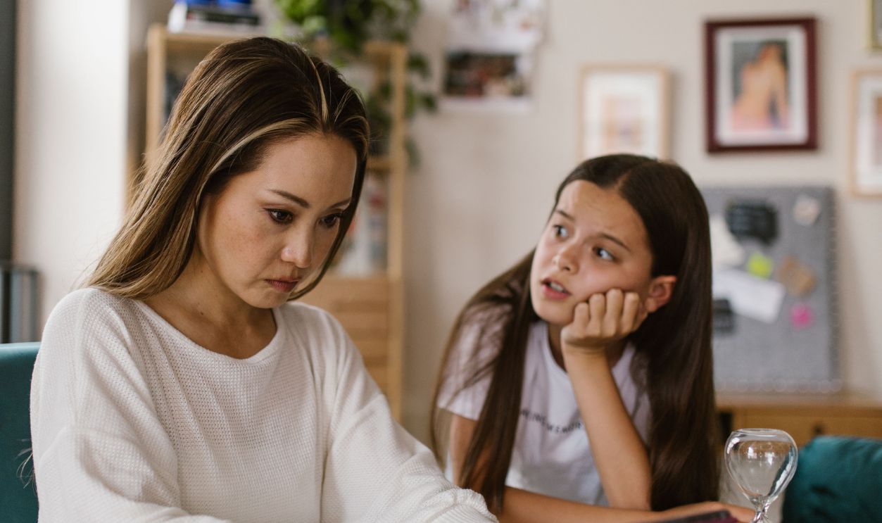 Woman focused on tablet work while child looks on, in a home office 