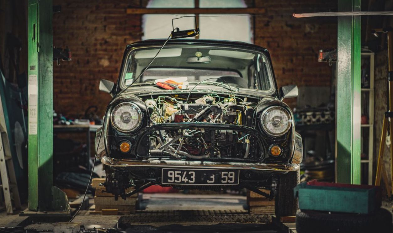 Front-view of a vintage car under repair in a classic workshop.