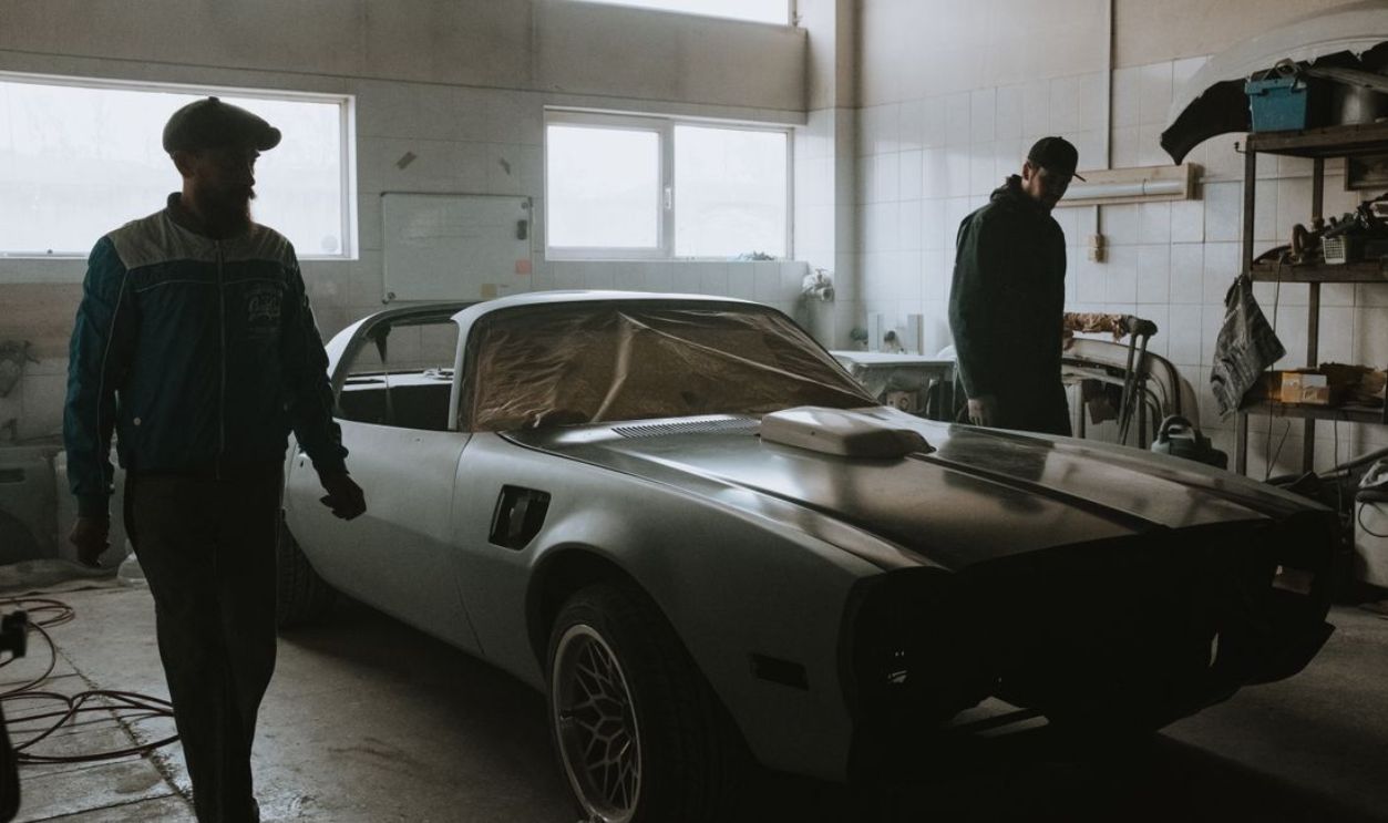 Mechanics working on a vintage car restoration in a dimly lit garage, capturing the essence of classic automotive care.