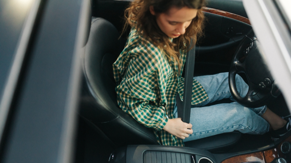 Young girl fastening her seat belt in the car. 