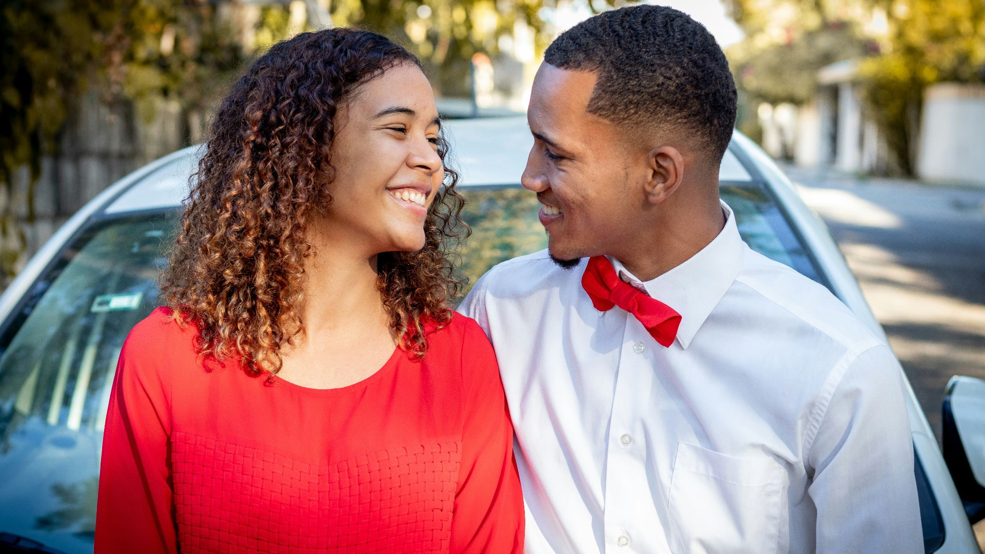 man in white dress shirt beside woman in red tank top