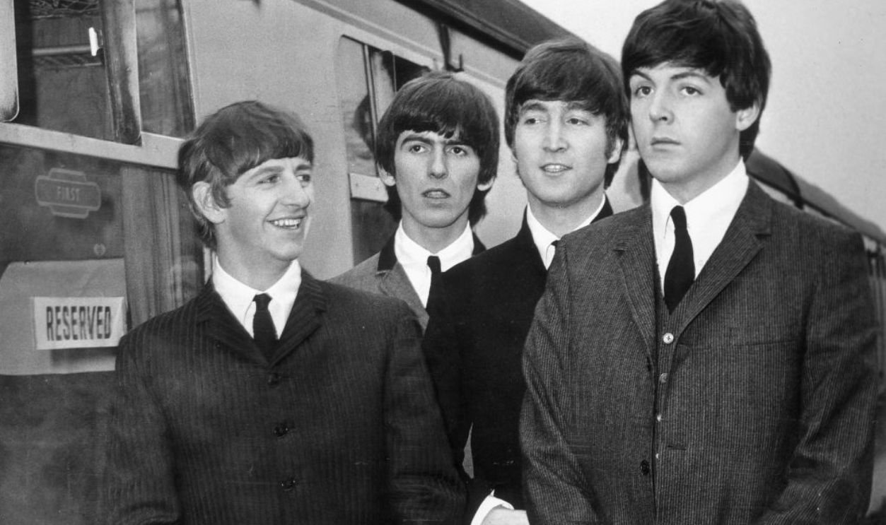 British rock group The Beatles stand next to a train on a station platform in Richard Lester's film 'A Hard Day's Night', 1964. Left to right, Ringo Starr, George Harrison, John Lennon (1940 - 1980) and Paul McCartney.