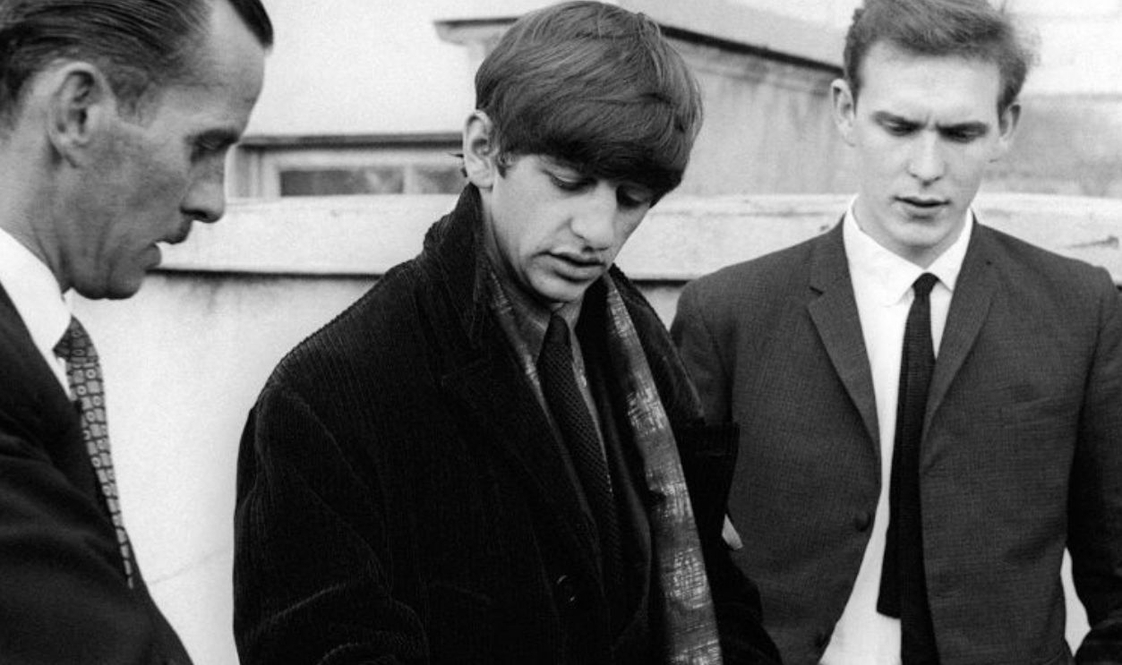 Ringo Starr is assisted with his luggage as The Beatles leave Portsmouth. 13th November 1963.