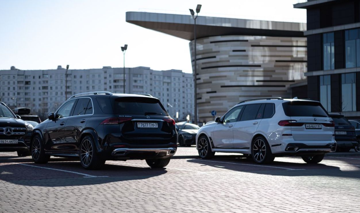 Two luxury SUVs parked in an urban setting with modern buildings in the background.