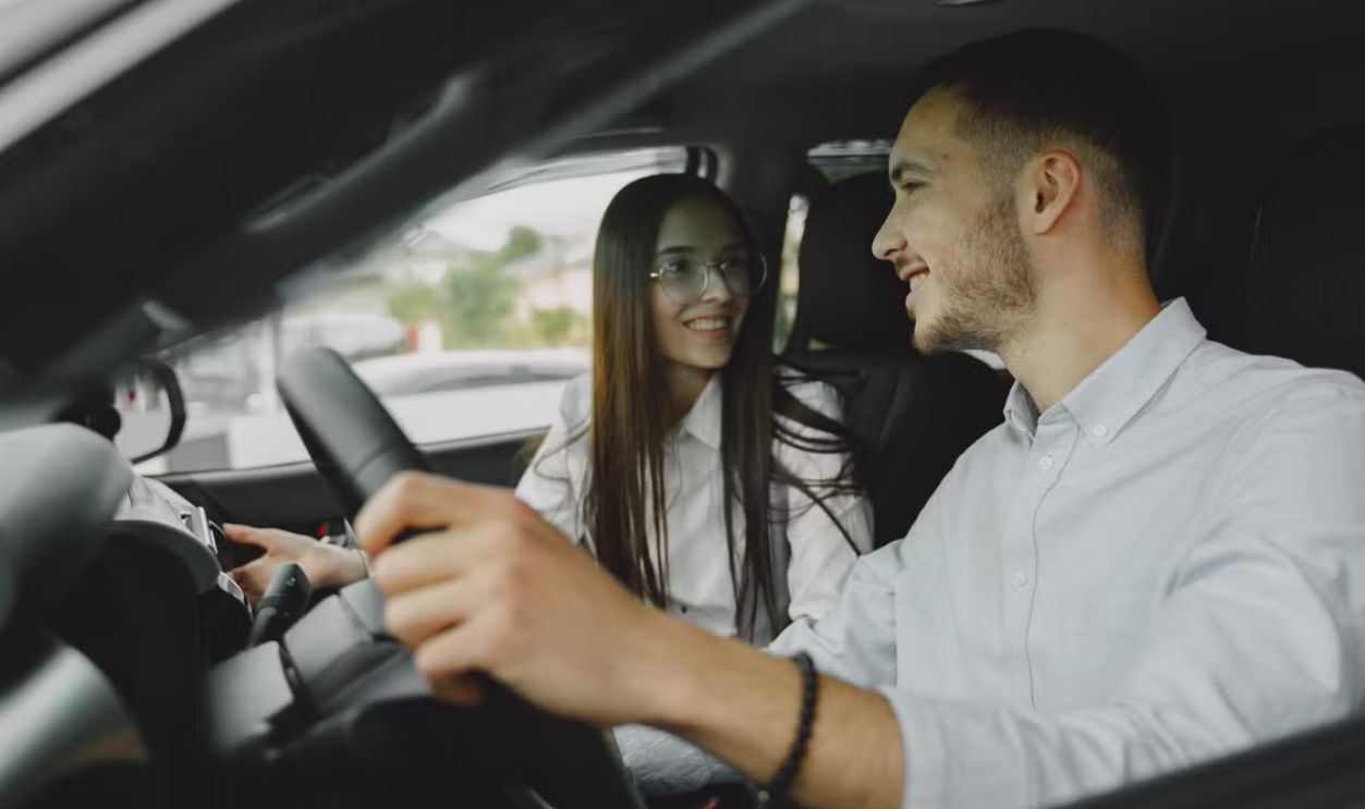 A smiling couple driving together in a car, enjoying their time on the road.