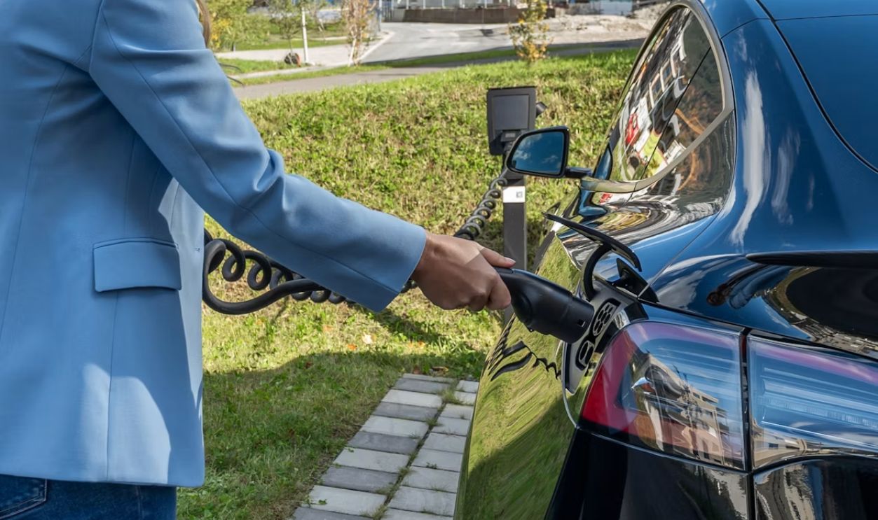 Person charging an electric car at charging station.
