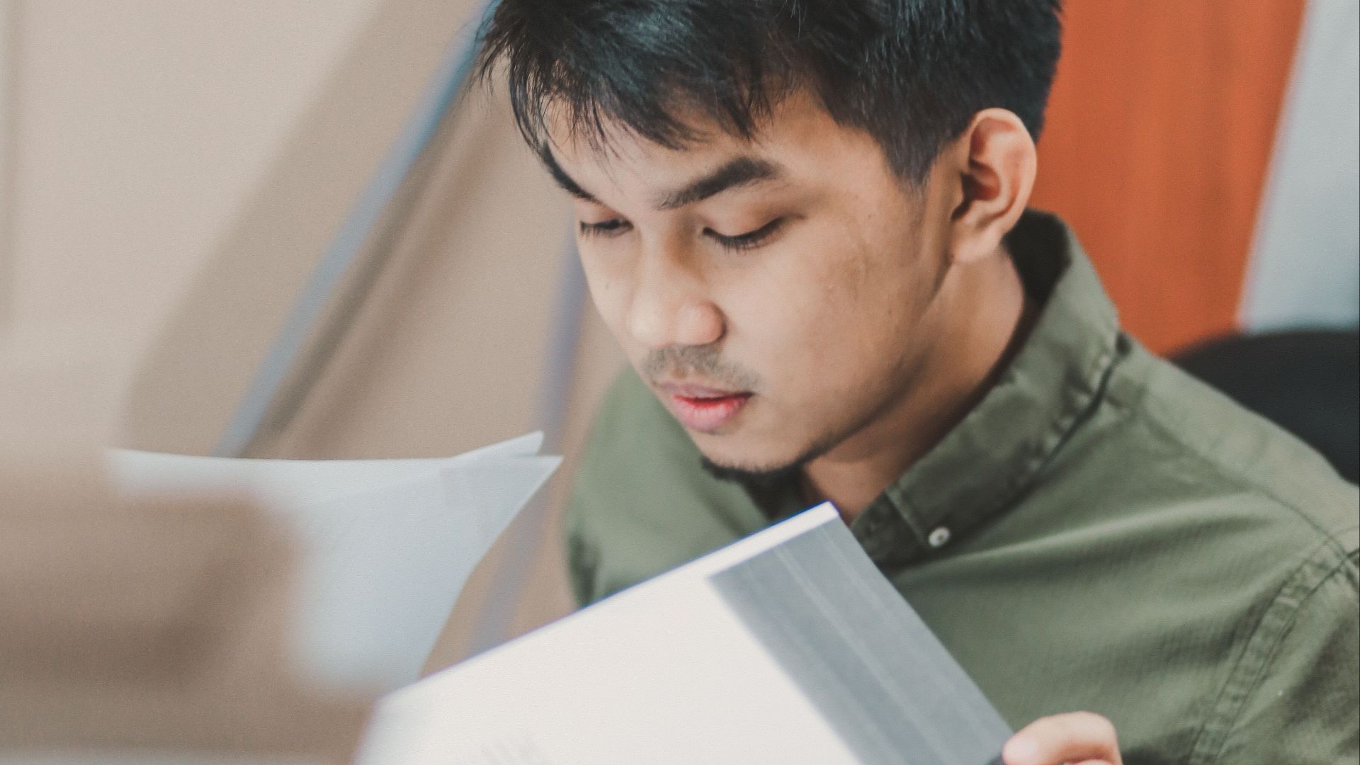 Young man intently reading documents at a desk, embodying concentration and work focus.