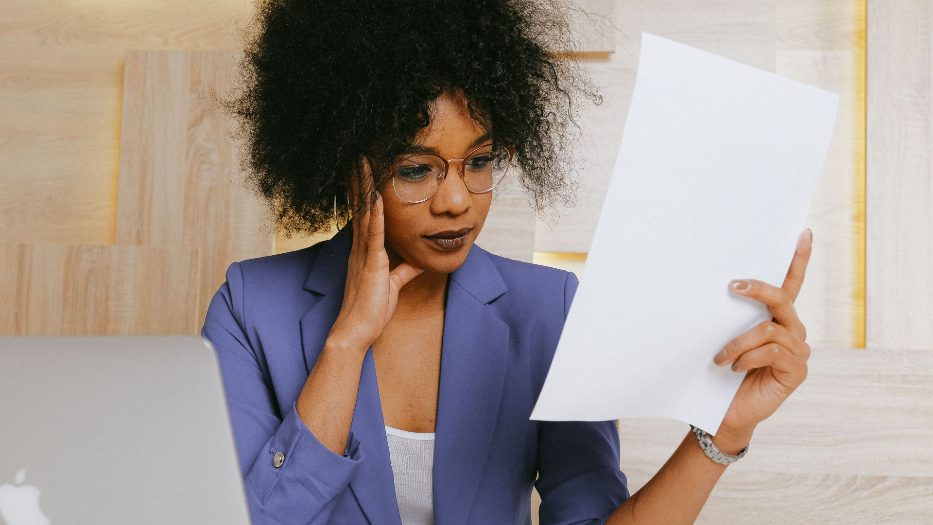 Businesswoman working on a laptop and reviewing a document at the office.