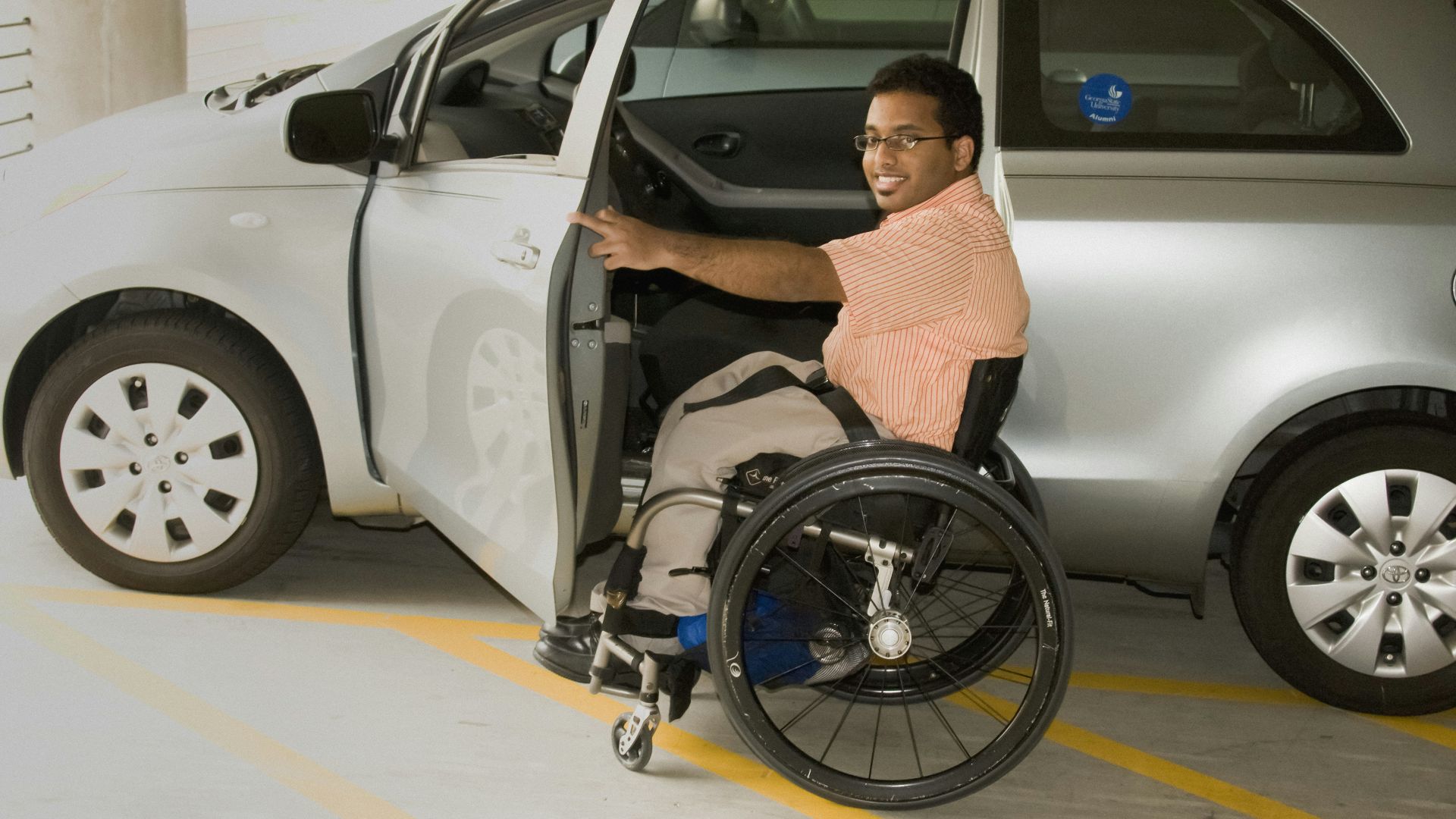 a man in a wheel chair next to a car