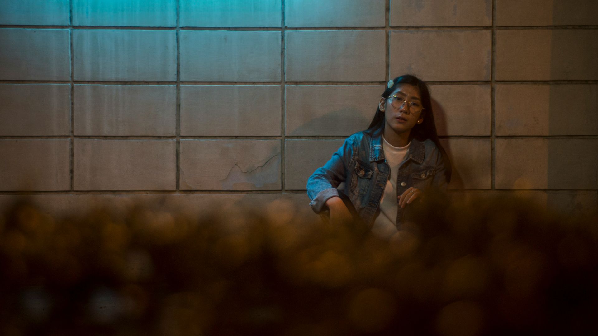 woman in blue denim jacket standing beside wall