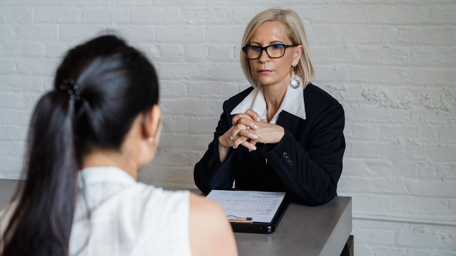 Professional businesswoman in a black blazer conducting an interview indoors.