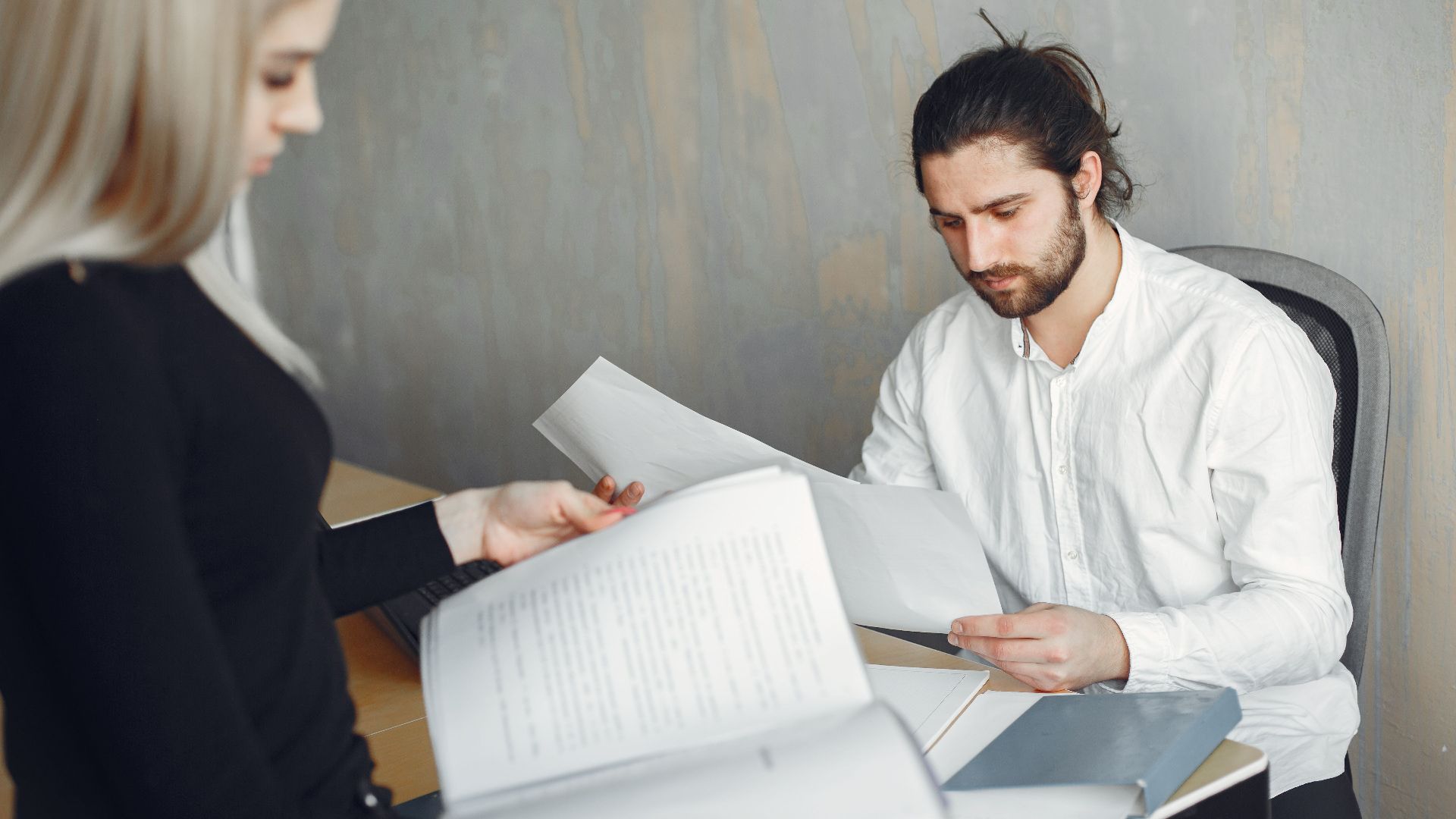 Two professionals reviewing important documents in a modern office setting.