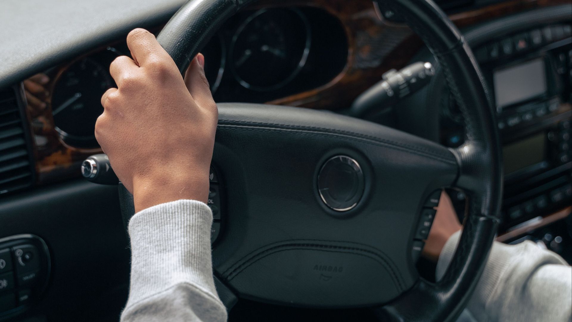 Hands on steering wheel inside a car, showcasing vehicle interior design.