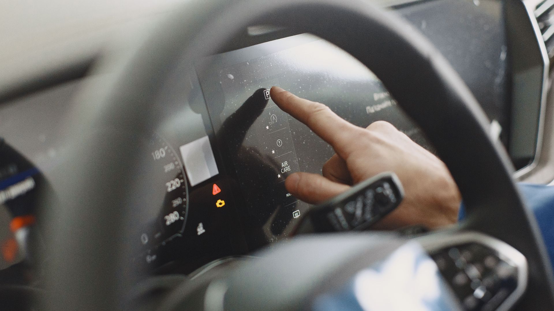Close-up of a hand interacting with a car's digital dashboard. Modern technology and driving interface.