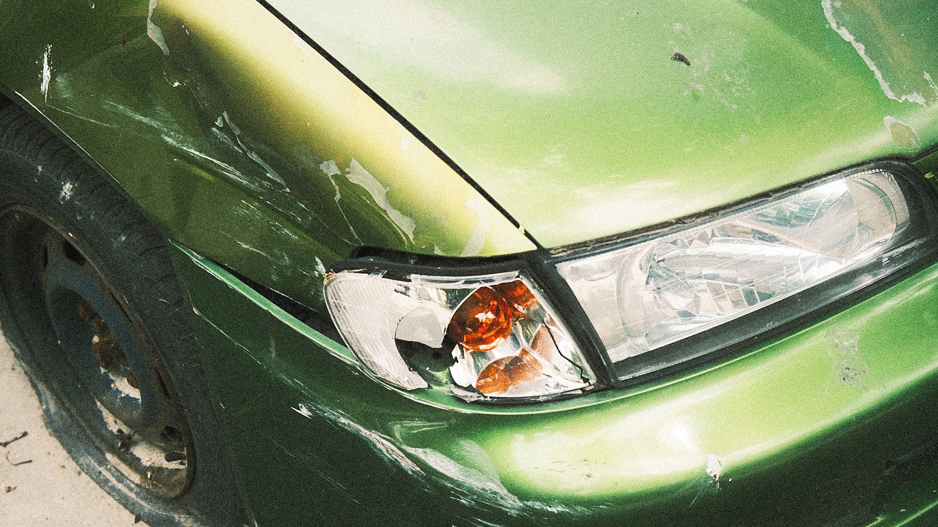 a green car with a dented front bumper