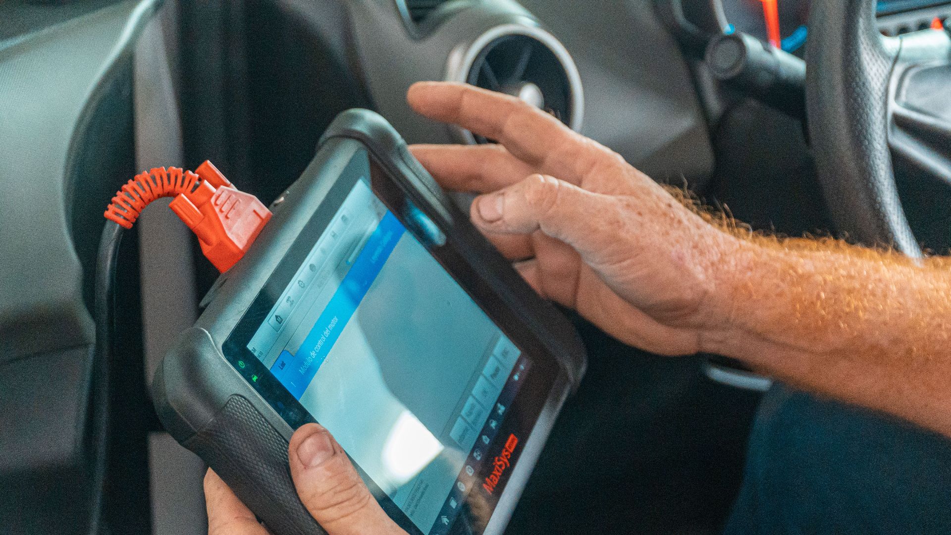 A mechanic uses a diagnostic tablet inside a car for vehicle analysis.
